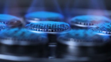 Karanlık ve tane işlenmiş karanlıkta gaz sobası üzerinde yanan ateş için yakın çekim başlangıç ateşleme