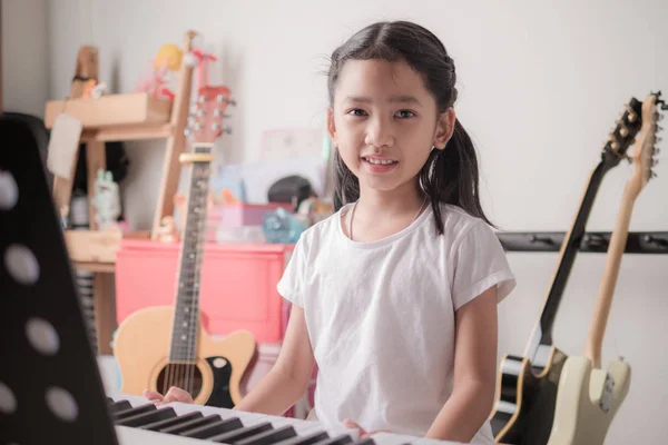 Asian little girl learning to play piano keyboard synthesizer an — Stock Photo, Image