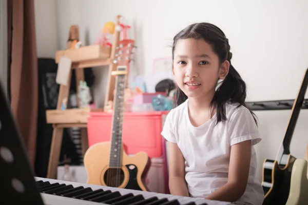 Asian little girl learning to play piano keyboard synthesizer an — Stock Photo, Image