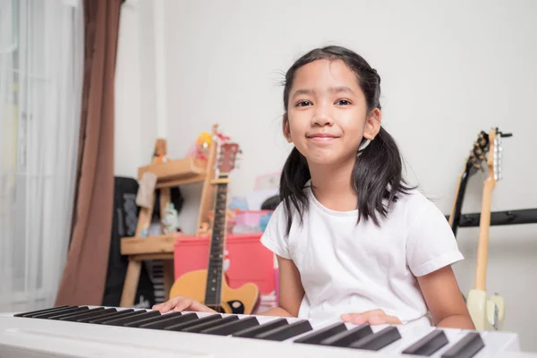 Asian little girl learning to play piano keyboard synthesizer wi — Stock Photo, Image