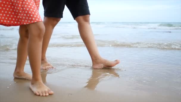 慢动作亚洲小女孩与母亲走在海滩与自然海浪海岸为暑假概念 — 图库视频影像