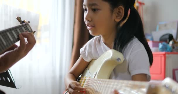 初心者の音楽楽器の自己学習のためのエレキギターを使用して基本的なギターを演奏することを学ぶアジアの小さな女の子に教える父 ギターを演奏する幸せな家族 — ストック動画