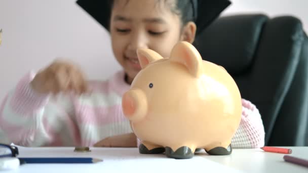 Kleine Asiatische Mädchen Puttinwg Die Münze Sparschwein Und Lächeln Vor — Stockvideo