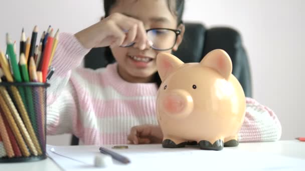 Kleine Asiatische Mädchen Puttinwg Die Münze Sparschwein Und Lächeln Vor — Stockvideo