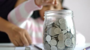 Küçük Asyalı kız kumbara içine sikke puttinwg ve eğitim kavramının gelecekte zenginlik tasarruf için mutluluk ile gülümseme alan odak sığ derinlik seçin