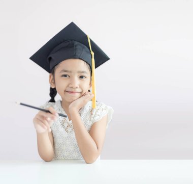 Portre küçük Asyalı kız lisansüstü şapka ve gülümseme zekâ giyiyor