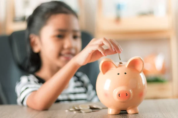 Asian little girl in putting coin in to piggy bank shallow depth — Stock Photo, Image