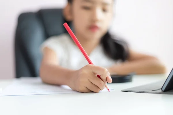 Маленькая азиатская девочка с помощью карандаша, чтобы написать на бумаге делает ч — стоковое фото