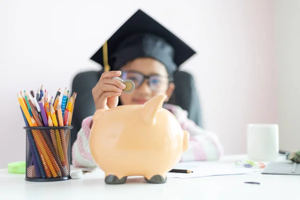 Pequeña chica asiática poniendo la moneda en alcancía y sonreír ingenio — Foto de Stock