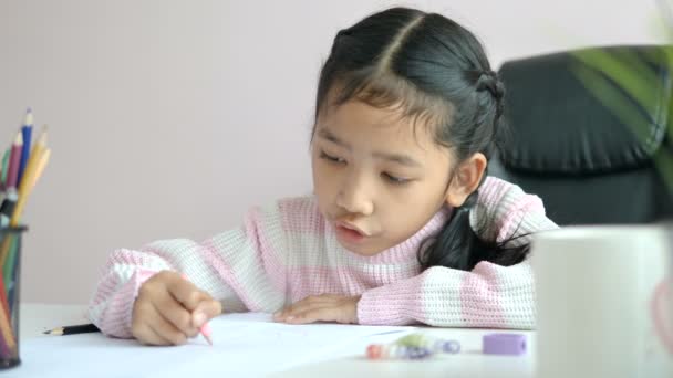教育の概念のための幸福と宿題や笑顔を行う紙に書くために鉛筆を使用して小さなアジアの女の子は フィールドの浅い深さを選択します — ストック動画