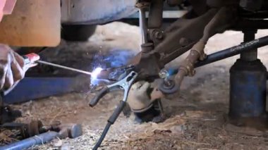  Lades kemiği kontrol kolunu onarmak ve arabanın ön tekerleğini değiştirmek için kamyonu kaynaklamak için kaynakçı kullanan tamirci