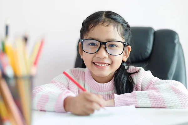 Liten asiatisk tjej gör läxor och leende med lycka för Ed — Stockfoto