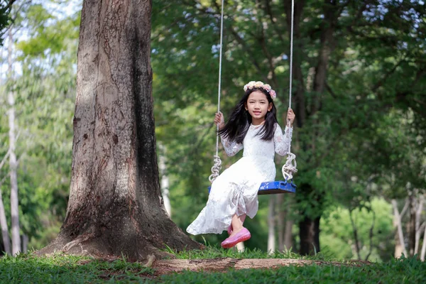 Retrato de niña asiática jugando el swing bajo el gran tr — Foto de Stock