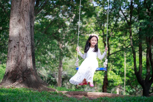 Retrato de niña asiática jugando el swing bajo el gran tr — Foto de Stock