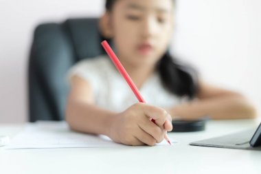 Küçük Asyalı kız h yapıyor kağıt üzerine yazmak için kalem kullanarak