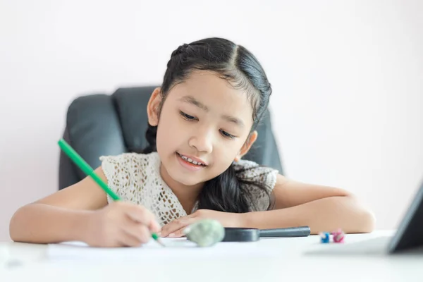 Pequeña chica asiática usando el lápiz para escribir en el papel haciendo h — Foto de Stock