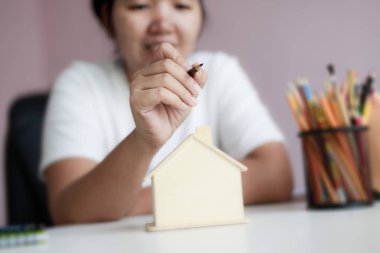 Mutlu Asyalı kadın kalem çizmek ve ahşap ev p ile plan kullanarak