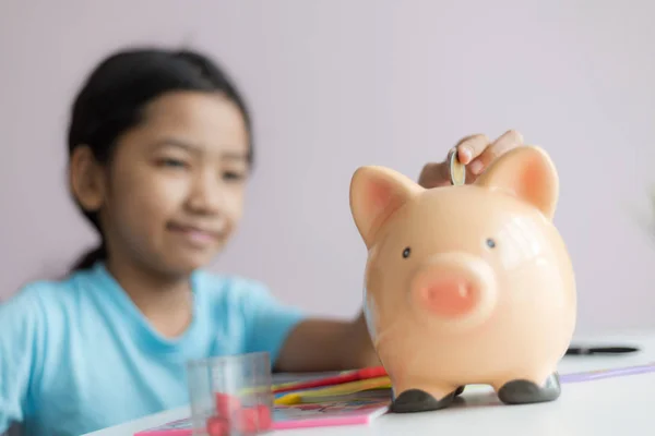 Happy little asian girl putting money coin into piggy bank selec — Stock Photo, Image