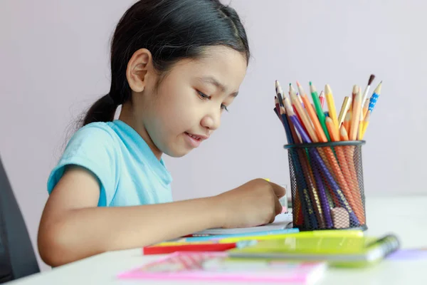 Pequeña chica asiática poniendo haciendo tarea uso de lápiz de color a dra —  Fotos de Stock