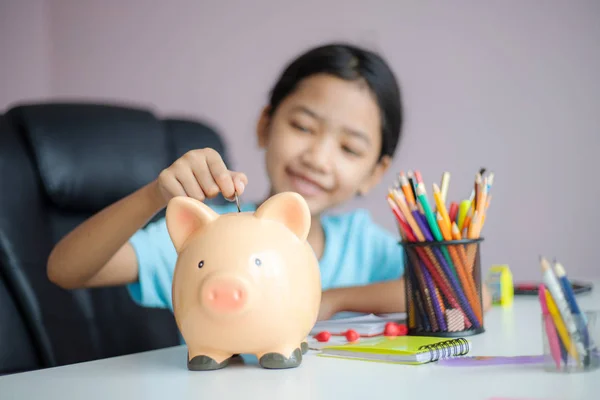 Happy little asian girl putting money coin into piggy bank selec — Stock Photo, Image