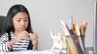 Asyalı küçük kız ahşap maket yapıyor. Sığ alan derinliğini seç.