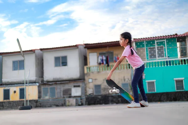 Asiatique petite fille tenant skateboard et sourire avec bonheur à — Photo