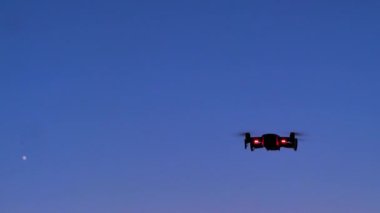 İnsansız hava aracı alacakaranlıkta fotoğraf ve video çekmek için uçuyor. Karanlık ve tahıl işlenmiş.