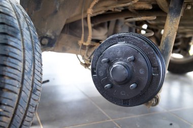 Lastik ve tekerleği söktükten sonra arabanın arka merkezi, fren ve tekerlek sistemi, araba tekerleği değiştirmek için kriko, yakın çekim.