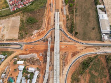 Vinç işçileri, traktörler ve kepçeler tarafından kavşağın üzerine beton köprü inşa edilmeden önce inşaat alanı