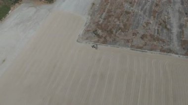 Drone videosu bir traktör cassava kurutma sahasına cassava yayıyor. Cassava un hazırlama süreci