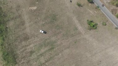 Kırsal bir yolda kırsal araziden geçen bir kamyonetin hava aracı görüntüsü. Doğada seyahat, ulaşım ve özgürlüğün manzaralı görüntüsü