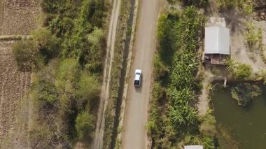 Kırsal bir yolda kırsal araziden geçen bir kamyonetin hava aracı görüntüsü. Doğada seyahat, ulaşım ve özgürlüğün manzaralı görüntüsü