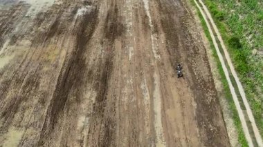 Drone tarladaki toprağı sürmek için küçük bir traktör kullanan çiftçileri görüntüler, geleneksel tarım ve kırsal yaşam tarzı kavramı