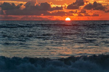 Güneş denizdeki ufukta yavaşça batıyor.