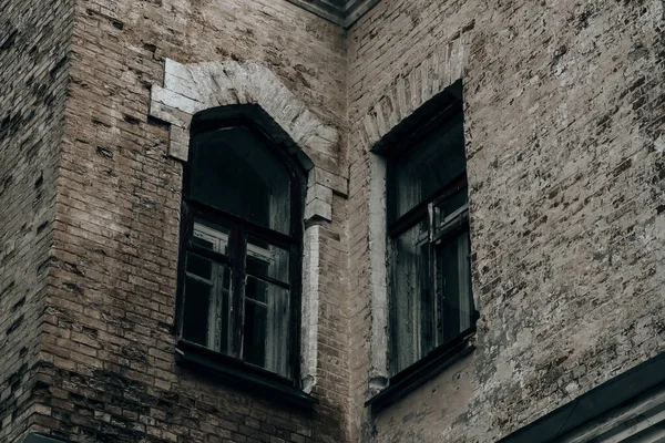 Terk edilmiş bir binada güzel pencereleri olan eski tuğla bir duvar.
