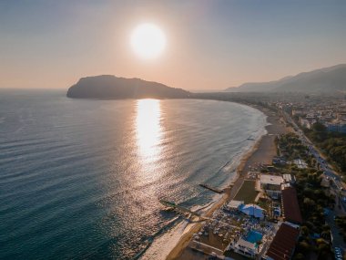 Akşam güneşi denizin ötesindeki dağın üzerinde batıyor.