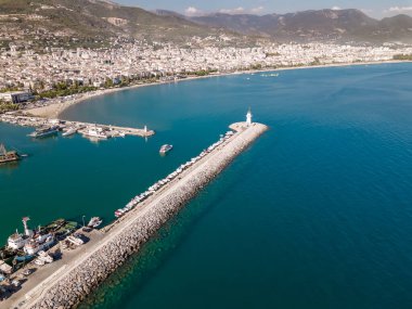 Deniz feneri ve arka planda dağlar olan güzel bir sahil.