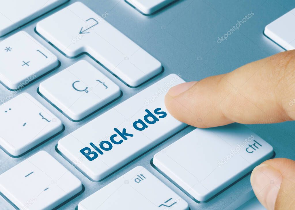 Block ads Written on Blue Key of Metallic Keyboard. Finger pressing key.