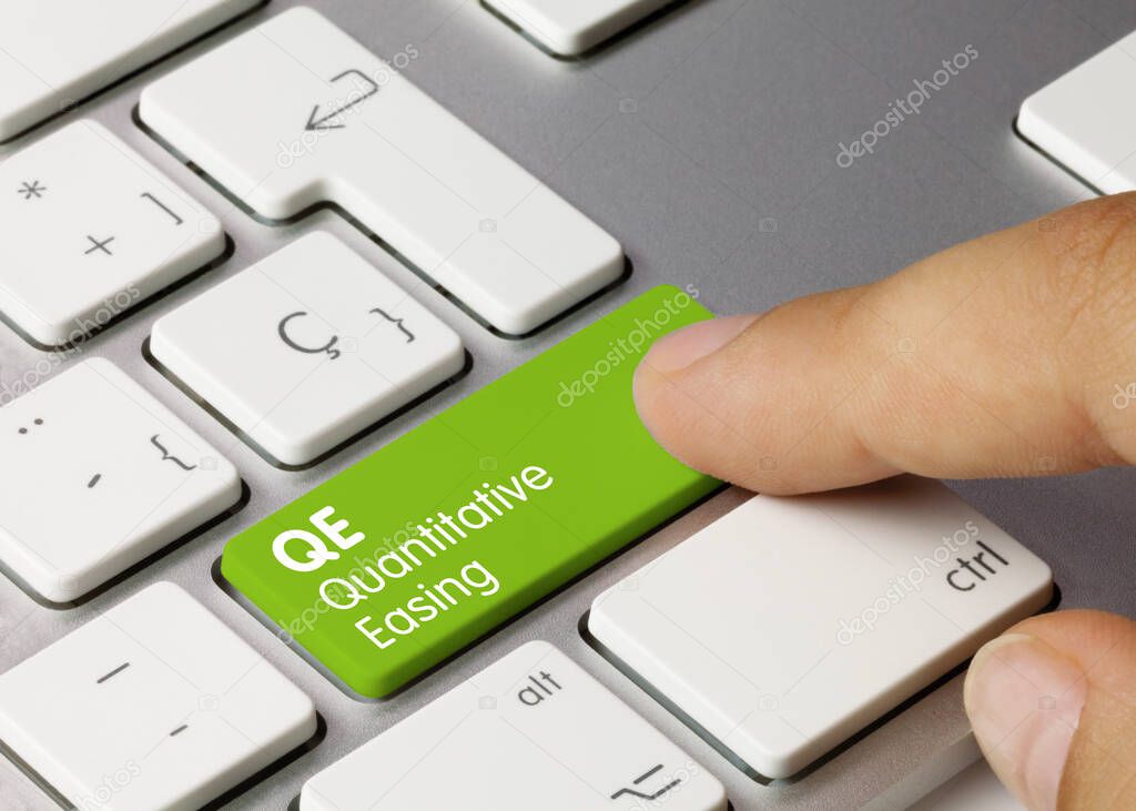 QE Quantitative Easing Written on Green Key of Metallic Keyboard. Finger pressing key.