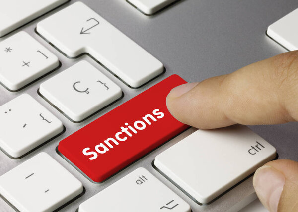 Sanctions Written on Red Key of Metallic Keyboard. Finger pressing key.