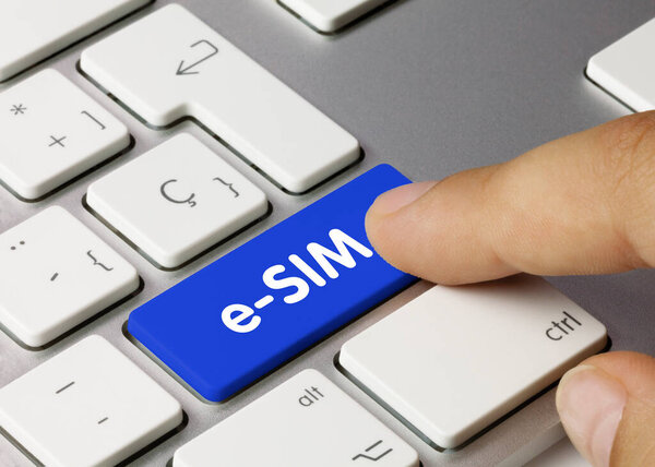 eSIM Written on Blue Key of Metallic Keyboard. Finger pressing key.