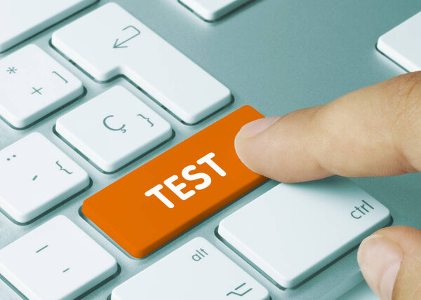 TEST Written on Orange Key of Metallic Keyboard. Finger pressing key.