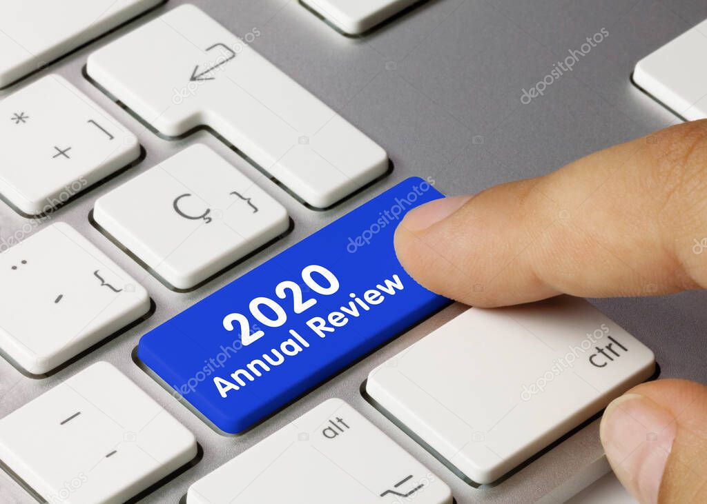 2020 Annual review Written on Blue Key of Metallic Keyboard. Finger pressing key.