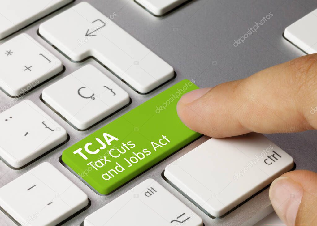 TCJA Tax Cuts and Jobs Act Written on Green Key of Metallic Keyboard. Finger pressing key.
