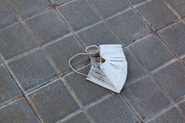 Şehirde yerde duran kullanılmış bir maskenin stok fotoğrafı. Maskeler çöp ve çöp olur.