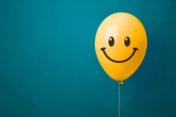 Foto Stock Globo Amarillo Con Cara Feliz Sobre Fondo Azul — Foto de Stock