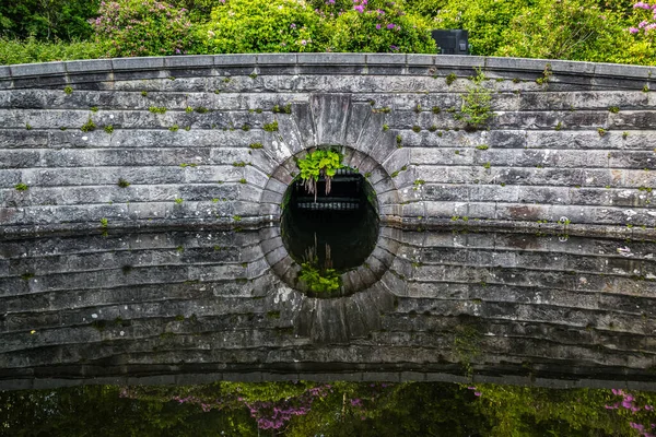 Detail of an old stone dam reflecting in water at Milngavie Waterworks, the water treatment facility located in Milngavie, Scotland.