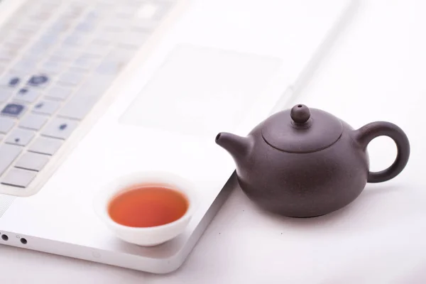 A cup of tea with the computer on background, close up