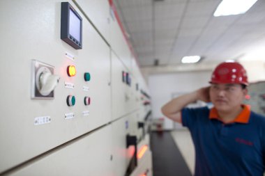 Elektrik işçisi kontrol odasındaki izleme cihazlarını izliyor.