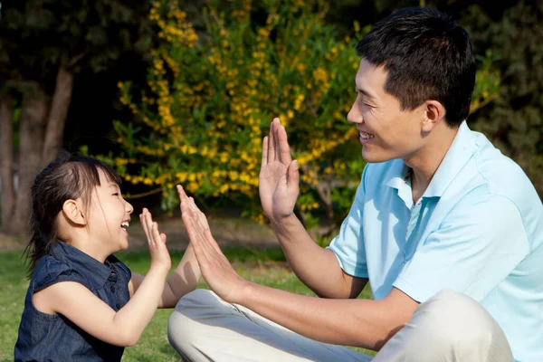 Father and daughter playing clapping games on grass